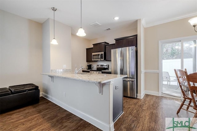 kitchen featuring a breakfast bar, hanging light fixtures, stainless steel appliances, dark hardwood / wood-style floors, and kitchen peninsula