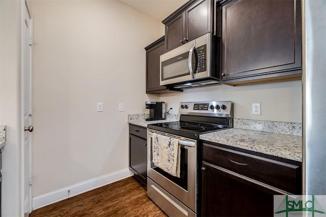 kitchen with stainless steel appliances, dark hardwood / wood-style flooring, light stone countertops, and dark brown cabinets