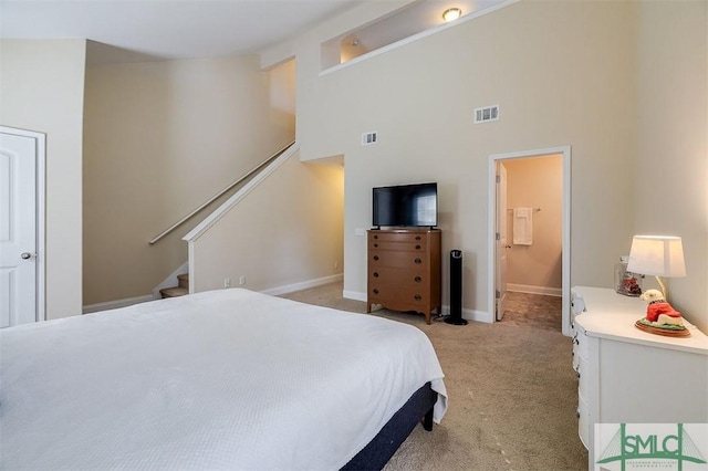 bedroom with a high ceiling and light colored carpet