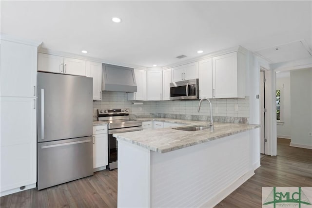 kitchen with wall chimney exhaust hood, stainless steel appliances, sink, and white cabinets