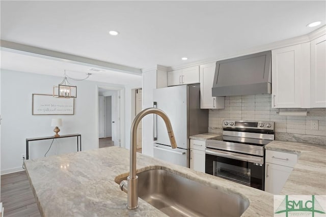 kitchen featuring white cabinetry, stainless steel electric stove, wall chimney exhaust hood, and refrigerator