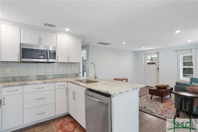 kitchen featuring sink, appliances with stainless steel finishes, kitchen peninsula, decorative backsplash, and white cabinets