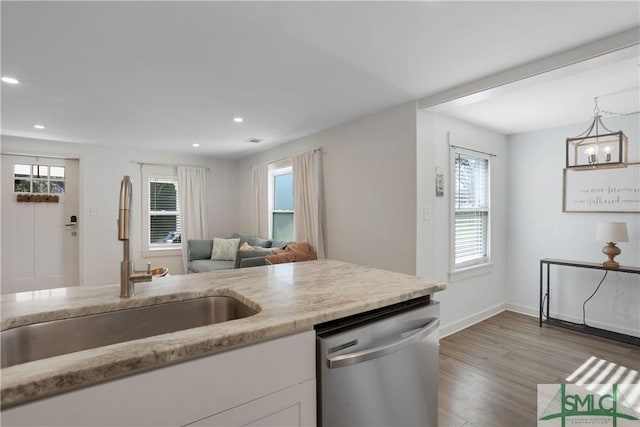 kitchen featuring sink, white cabinetry, decorative light fixtures, light wood-type flooring, and stainless steel dishwasher