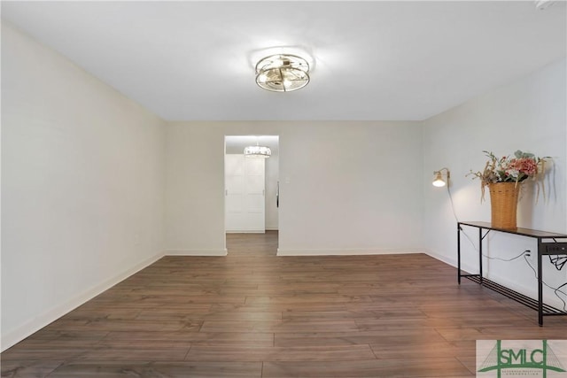 empty room featuring a notable chandelier and dark hardwood / wood-style flooring