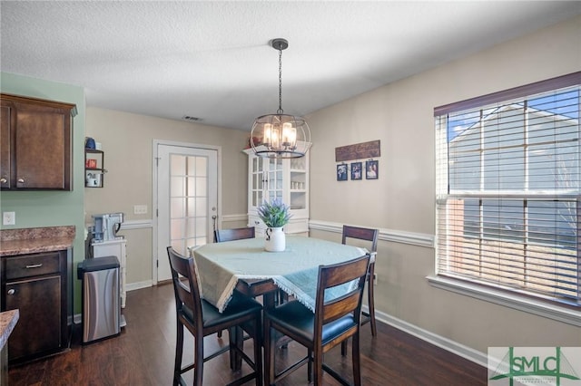 dining area featuring dark wood-type flooring and a textured ceiling