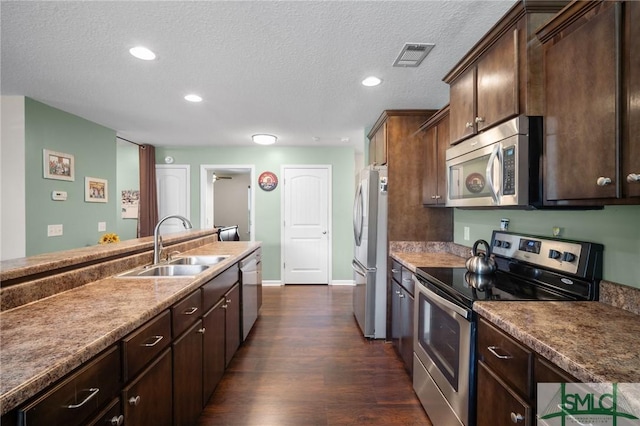 kitchen with stainless steel appliances, dark brown cabinets, sink, and dark hardwood / wood-style floors