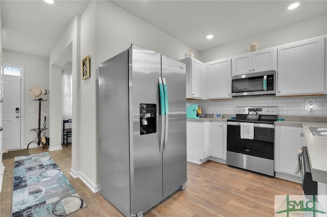 kitchen with stainless steel appliances, light hardwood / wood-style floors, decorative backsplash, and white cabinets