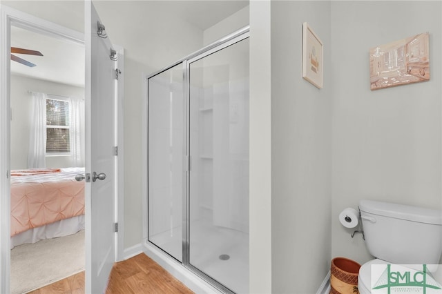 bathroom with wood-type flooring, toilet, and an enclosed shower