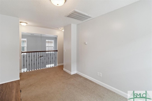 carpeted spare room with a textured ceiling