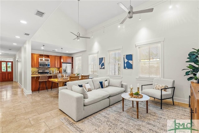 living room featuring ceiling fan, rail lighting, and a high ceiling