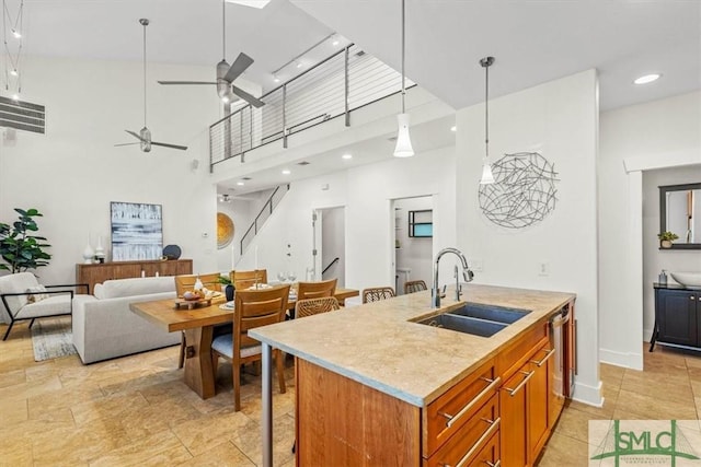 kitchen featuring decorative light fixtures, an island with sink, sink, stainless steel dishwasher, and ceiling fan