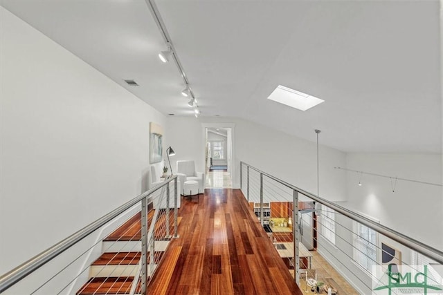 hallway with lofted ceiling with skylight, rail lighting, and wood-type flooring