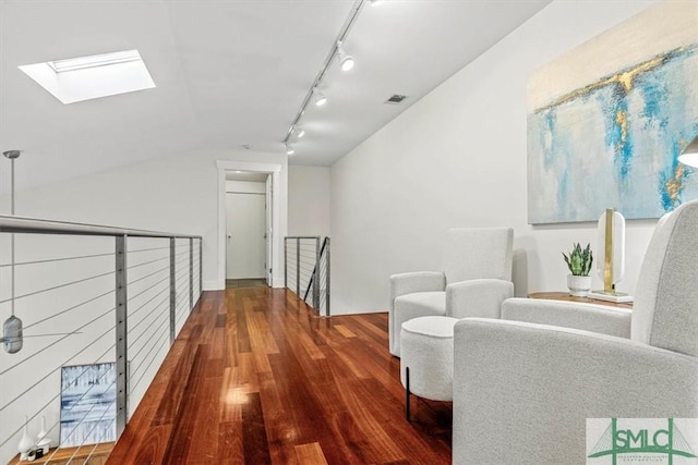 corridor with hardwood / wood-style flooring, rail lighting, and vaulted ceiling with skylight