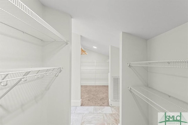 walk in closet featuring light colored carpet and vaulted ceiling