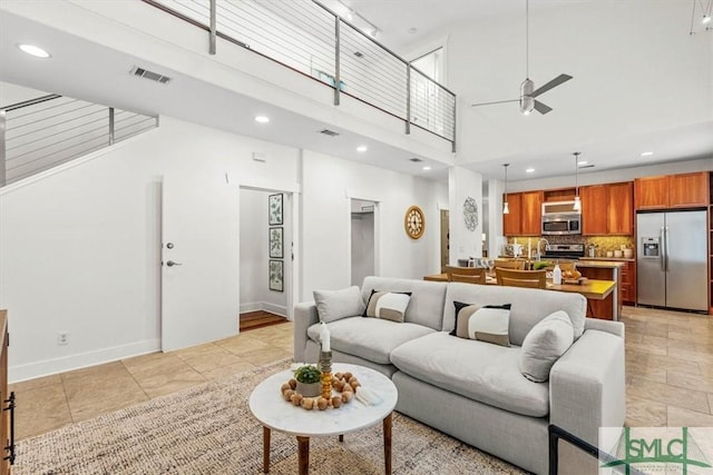 living room featuring ceiling fan and a high ceiling