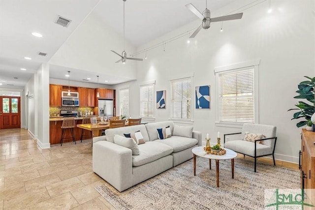 living room featuring ceiling fan, track lighting, and a towering ceiling