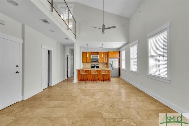 kitchen featuring a breakfast bar area, tasteful backsplash, decorative light fixtures, appliances with stainless steel finishes, and ceiling fan