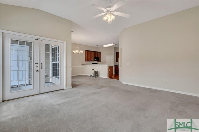 unfurnished living room with ceiling fan with notable chandelier, lofted ceiling, carpet floors, and french doors