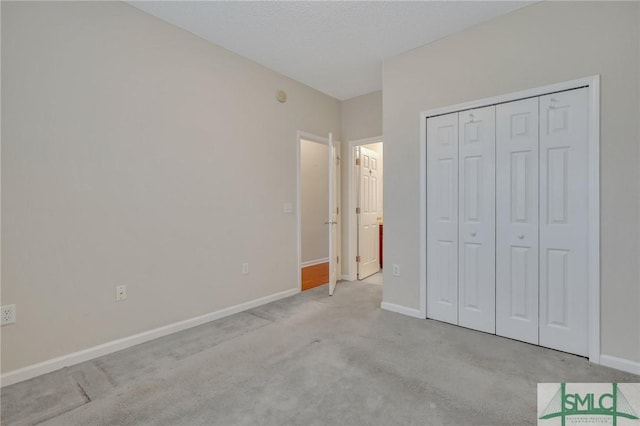 unfurnished bedroom with light colored carpet, a textured ceiling, and a closet