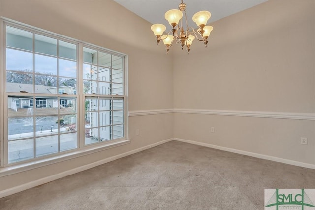 carpeted empty room featuring a chandelier