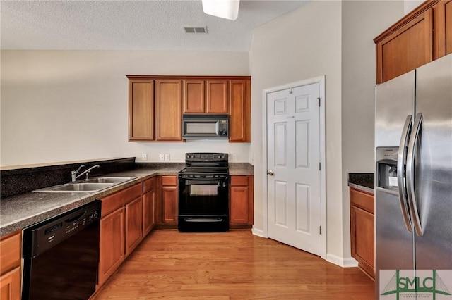 kitchen with light wood-type flooring, sink, a textured ceiling, and black appliances