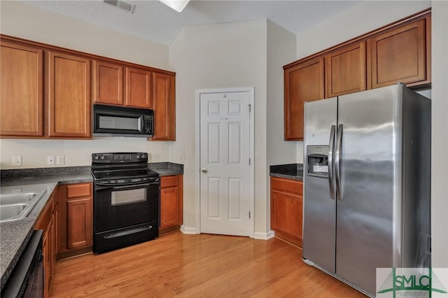 kitchen featuring sink, light hardwood / wood-style flooring, black appliances, and a textured ceiling