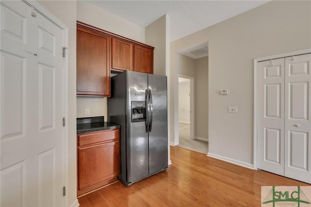 kitchen featuring light wood-type flooring, a textured ceiling, and stainless steel refrigerator with ice dispenser