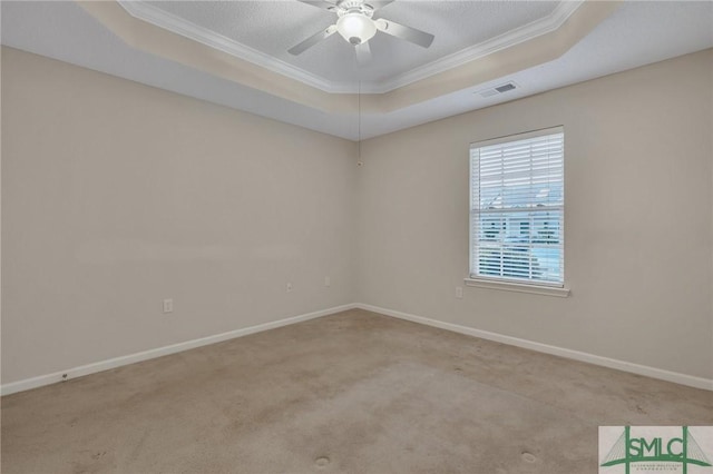 empty room with crown molding, ceiling fan, a raised ceiling, and light colored carpet