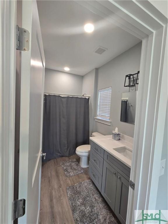 bathroom with hardwood / wood-style flooring, vanity, curtained shower, and toilet