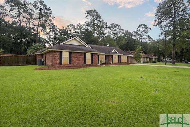 view of front of home with central AC unit and a lawn