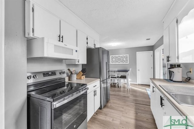 kitchen with sink, white cabinetry, a textured ceiling, light wood-type flooring, and appliances with stainless steel finishes