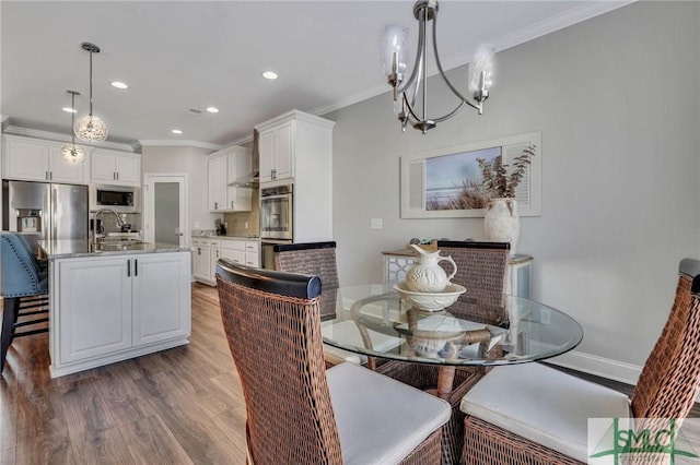 dining space with an inviting chandelier, sink, crown molding, and hardwood / wood-style floors