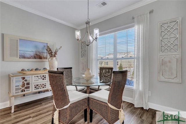 dining room with hardwood / wood-style flooring, crown molding, and an inviting chandelier