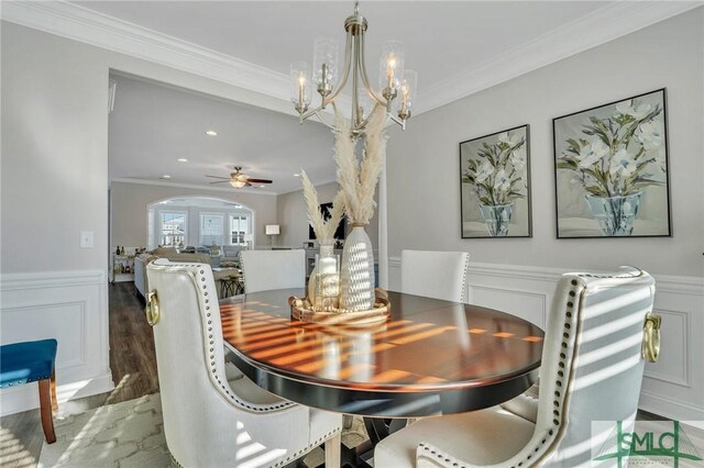 dining space featuring crown molding, ceiling fan with notable chandelier, and dark wood-type flooring