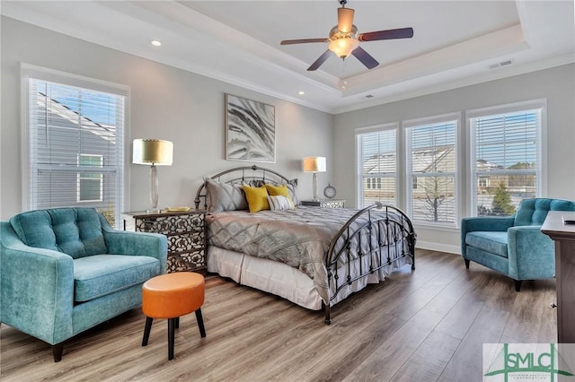 bedroom featuring ceiling fan, ornamental molding, a raised ceiling, and hardwood / wood-style floors