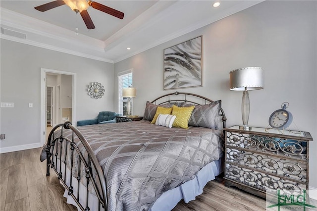 bedroom featuring hardwood / wood-style floors, a tray ceiling, ornamental molding, and ceiling fan