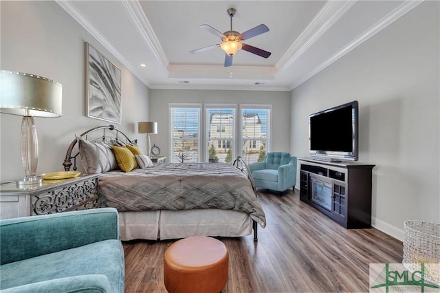 bedroom featuring a tray ceiling, wood-type flooring, ornamental molding, and ceiling fan