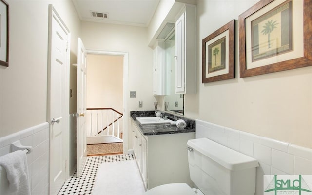 bathroom with vanity, toilet, and tile walls