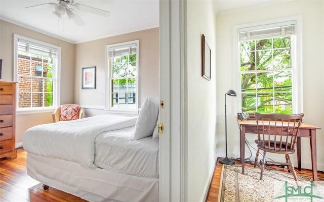 bedroom featuring multiple windows, hardwood / wood-style floors, and ornamental molding