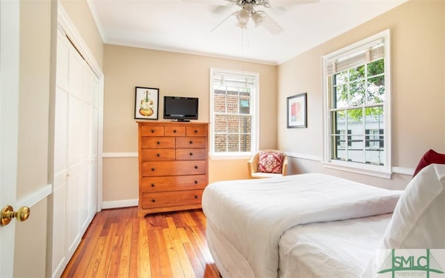 bedroom featuring a closet, ornamental molding, light hardwood / wood-style floors, and multiple windows