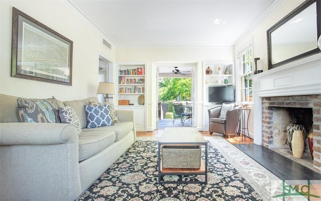 living room featuring a fireplace, hardwood / wood-style flooring, ornamental molding, and built in features