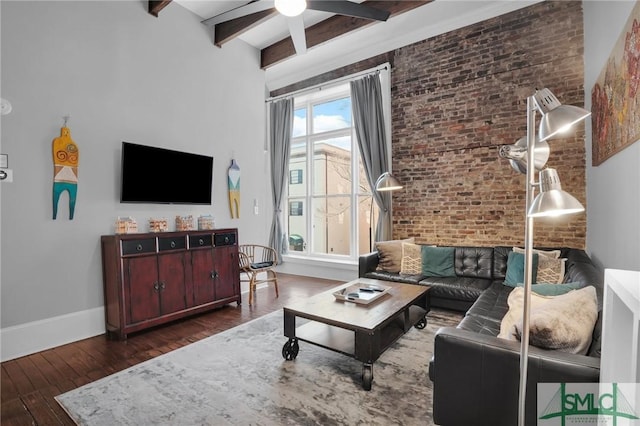 living room featuring beamed ceiling, brick wall, and dark hardwood / wood-style floors