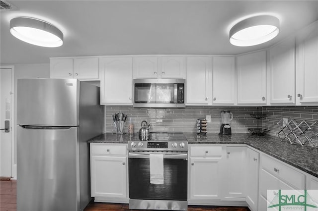 kitchen with white cabinetry, appliances with stainless steel finishes, and dark stone countertops