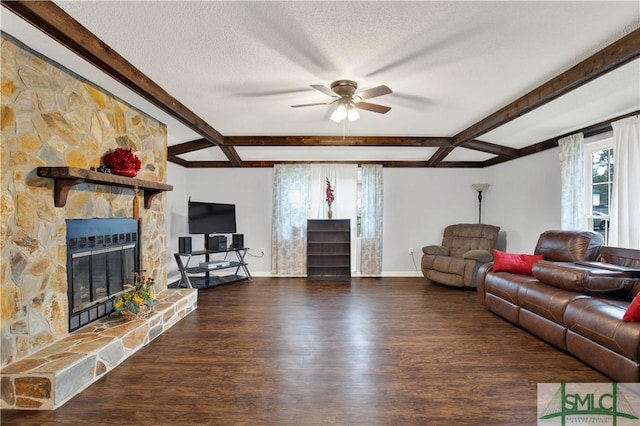 living room with a stone fireplace, ceiling fan, dark wood-type flooring, a textured ceiling, and beam ceiling