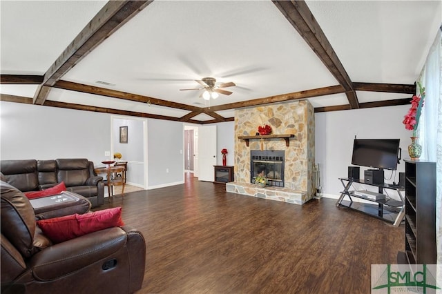 living room with hardwood / wood-style flooring, ceiling fan, a stone fireplace, and beam ceiling