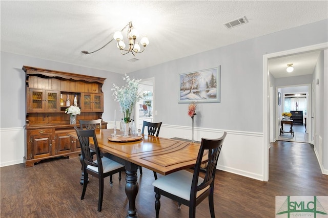 dining area with dark hardwood / wood-style flooring, a chandelier, and a textured ceiling