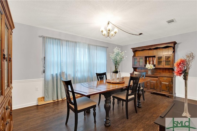 dining space featuring dark hardwood / wood-style flooring, a textured ceiling, and a chandelier