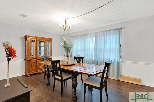 dining area featuring dark hardwood / wood-style flooring, a chandelier, and a textured ceiling