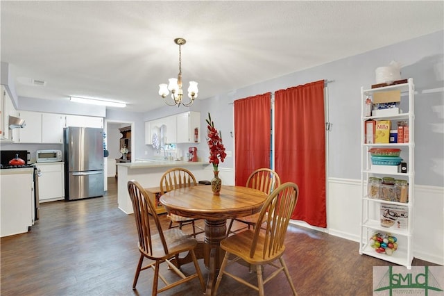 dining room with sink, dark wood-type flooring, and a chandelier