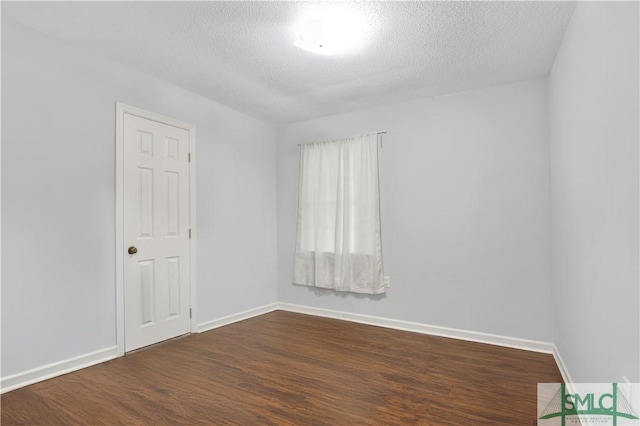 empty room featuring dark hardwood / wood-style flooring and a textured ceiling